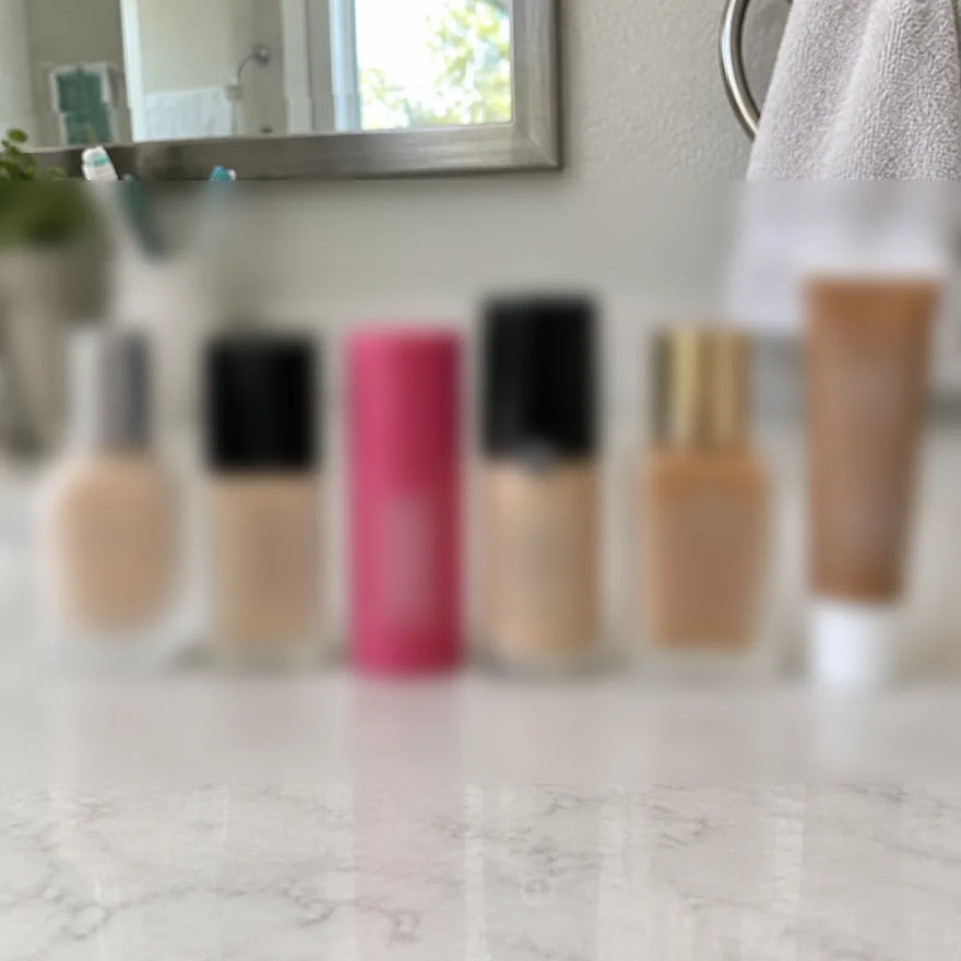 Six foundation bottles lined up on a bathroom counter
